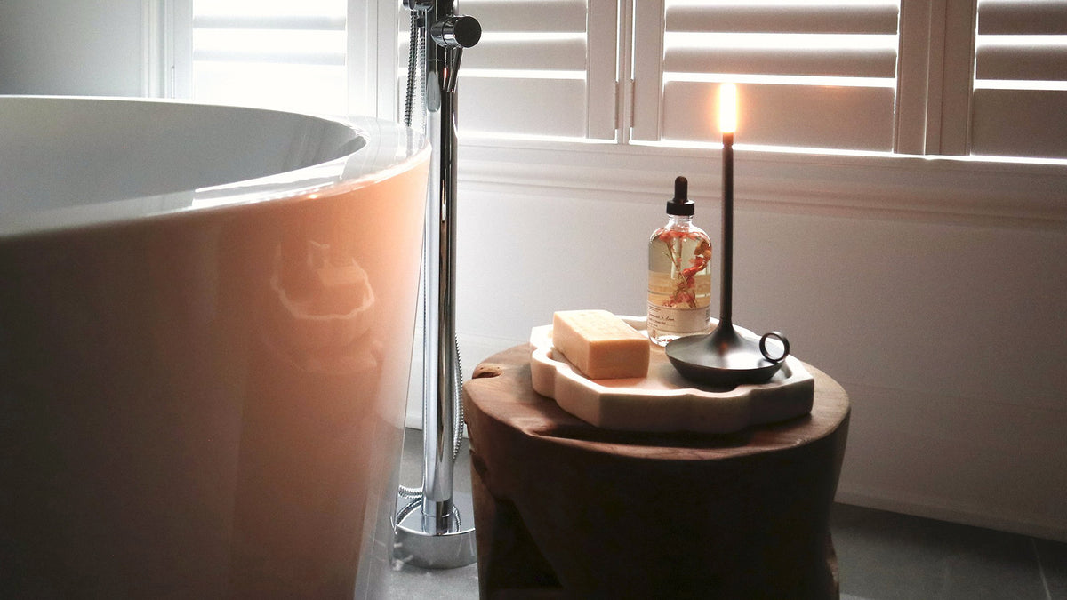 candle and soap on teak table beside white bathtub