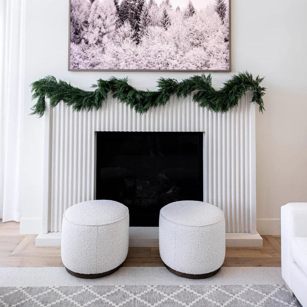 Decorative fireplace with greenery and a framed picture above it in a living room.