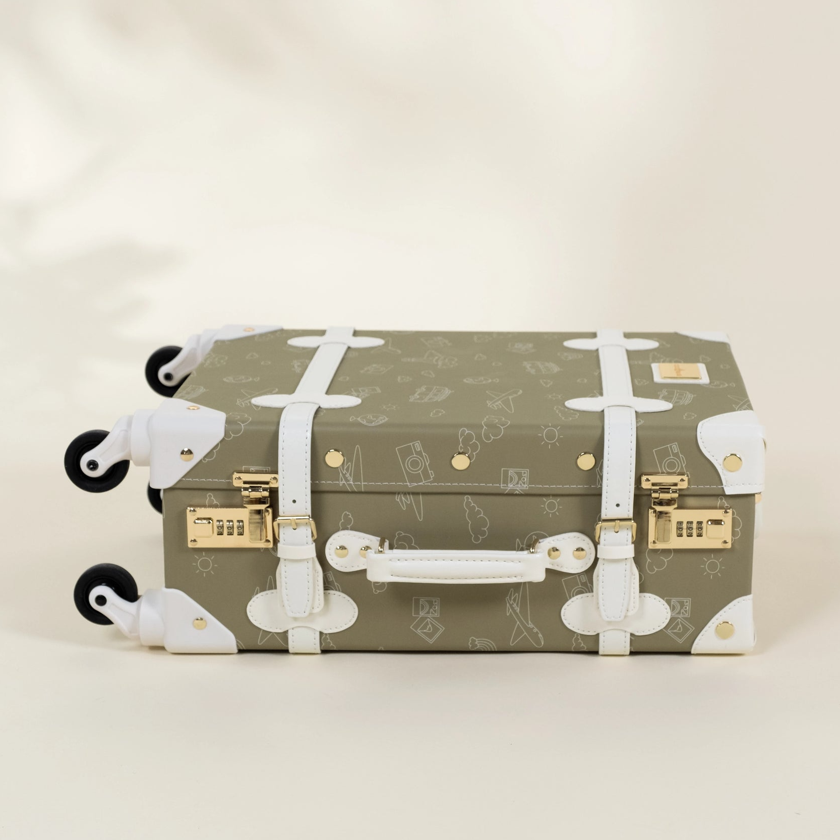 Green suitcase with white patterns on a beige background