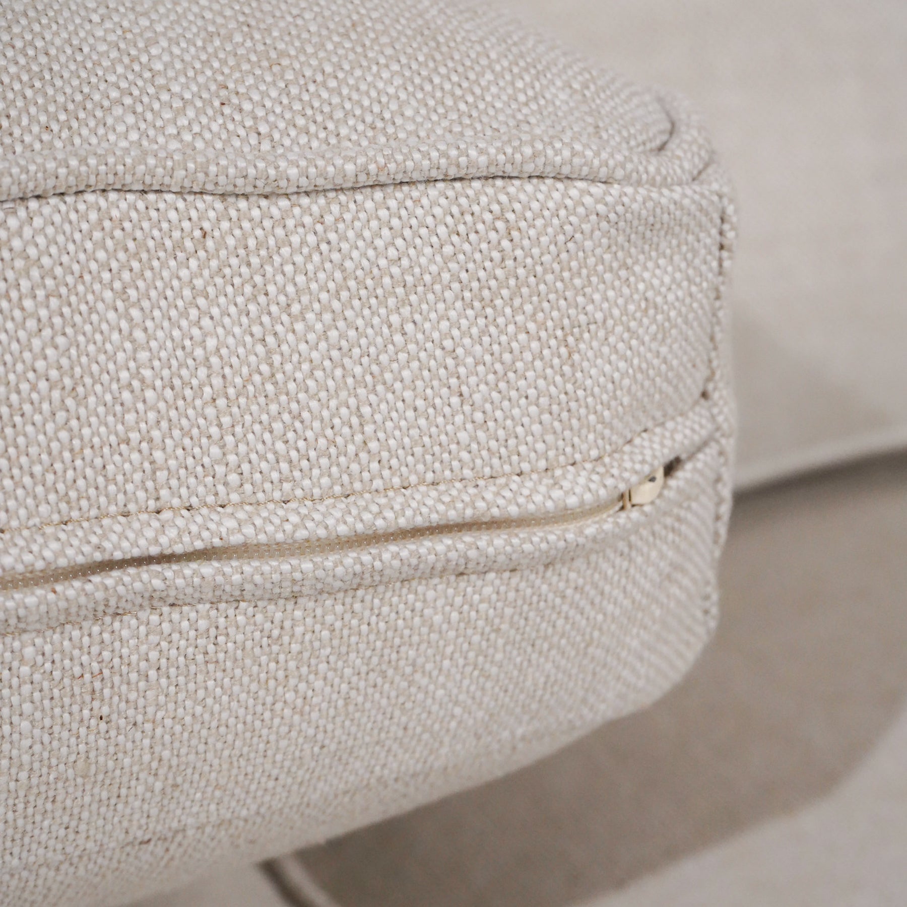 Close-up of beige fabric with visible stitching on a chair.