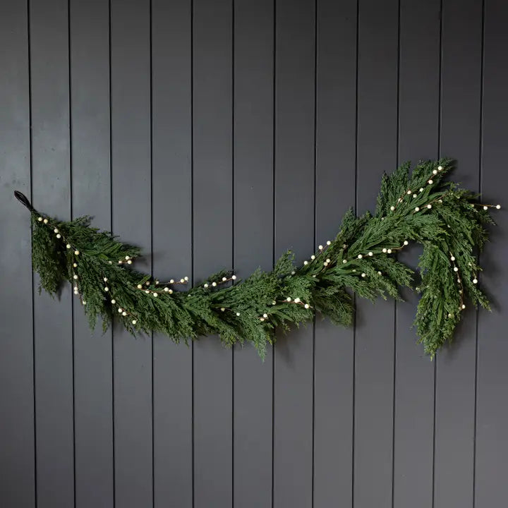 Green Christmas garland with lights on a black wooden background