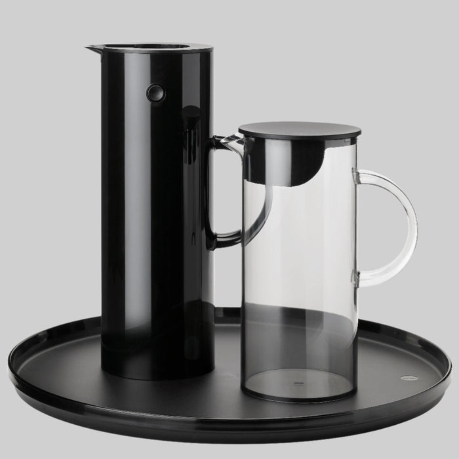 Black and clear glass coffee carafe set on a black tray with a gray background