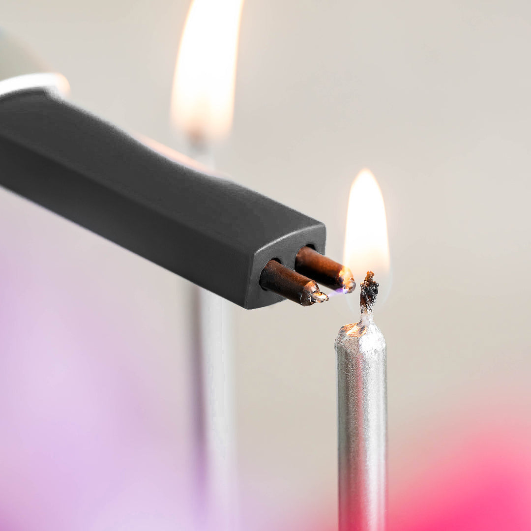 Black electronic lighter being lit with a match against a blurred background