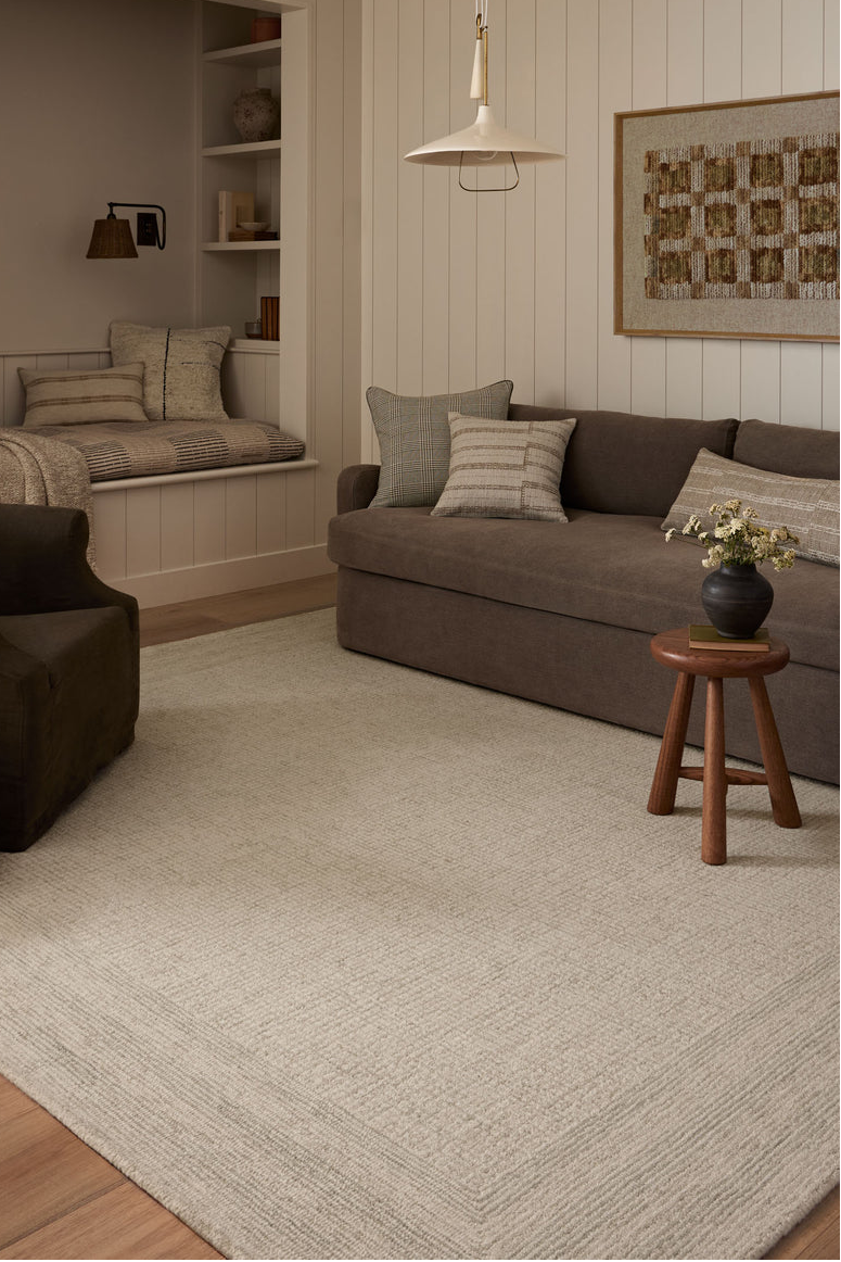 Cozy living room with brown sofa, armchair, and wooden stool.