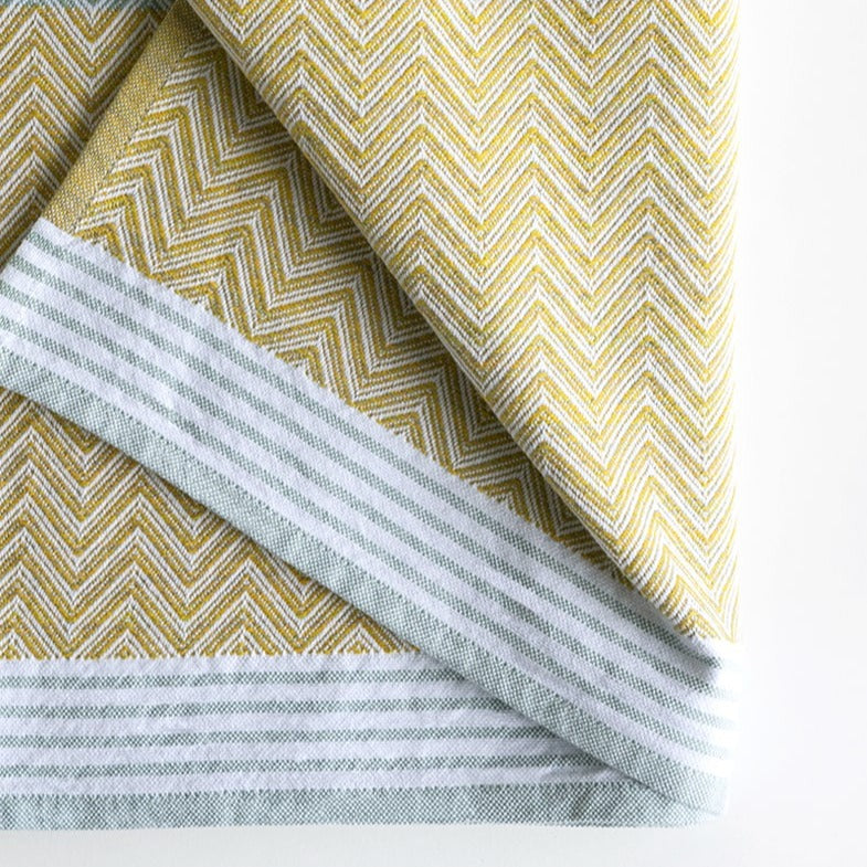 Premium one of kind cotton lemon coloured hand towel, intricate chevron pattern in warm yellow and banded with white and grey stripes at edge