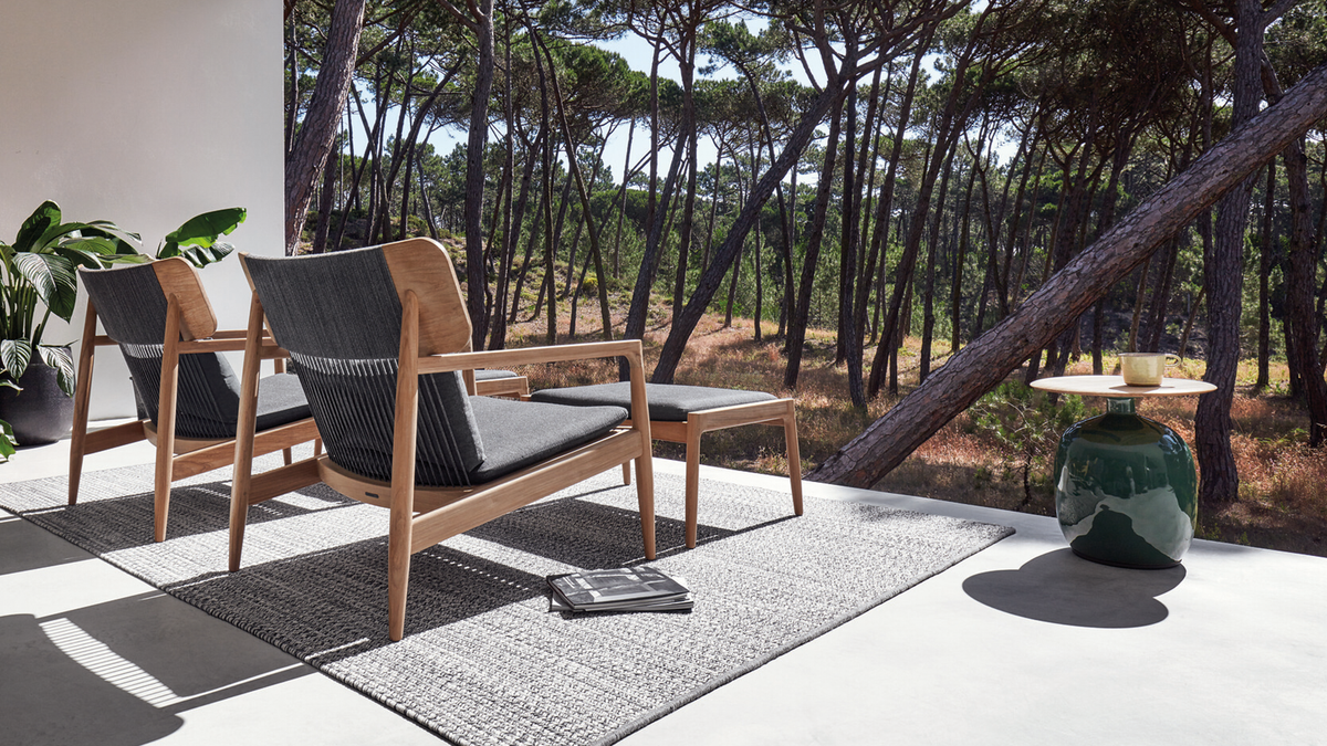 Gloster Archi outdoor lounge chairs and ottomans on back patio overlooking forest