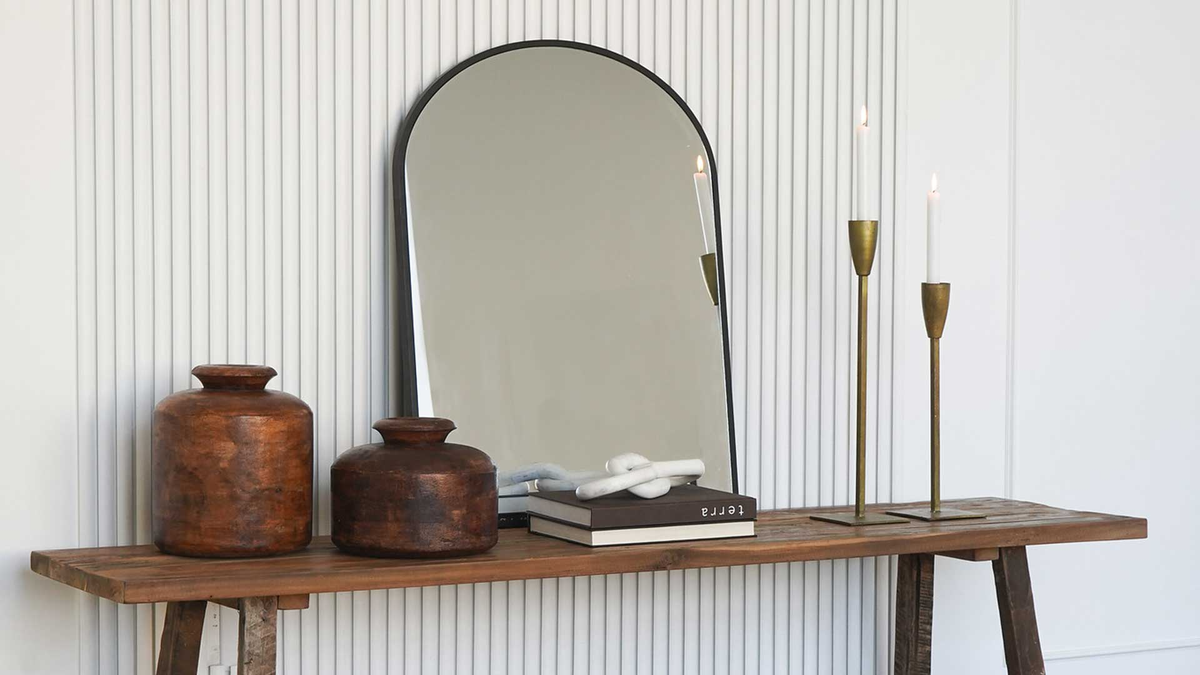 black rimmed arch mirror on console table
