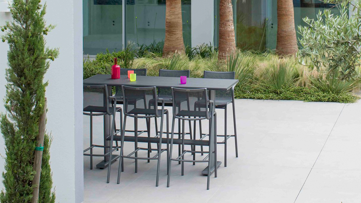 outdoor bar table and stools by palm trees
