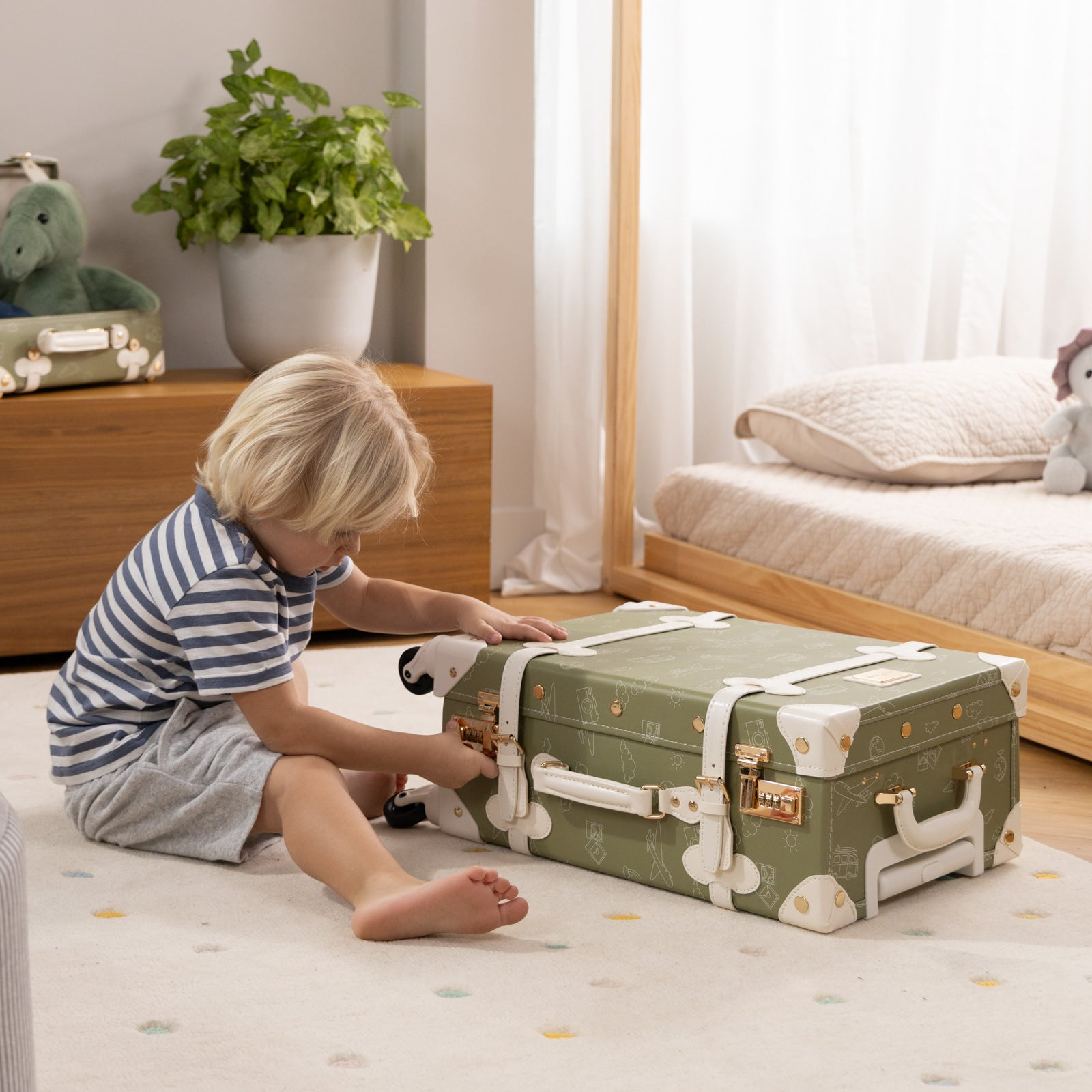 Child playing with a green suitcase on a bed