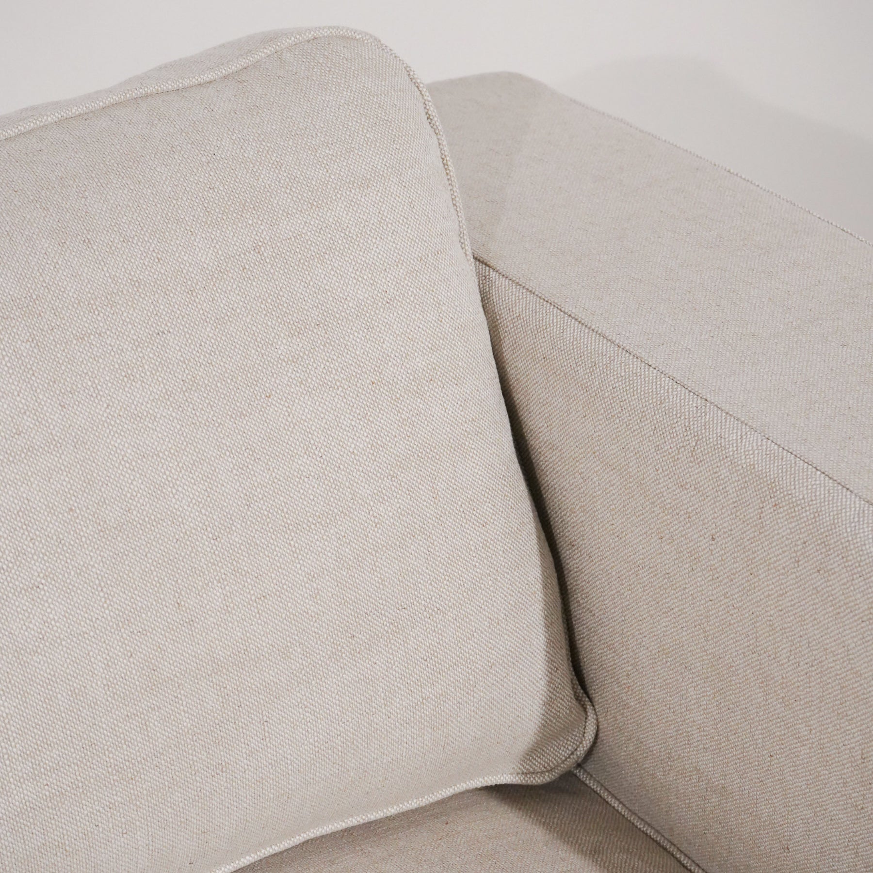Close-up of a beige fabric sofa with a pillow.
