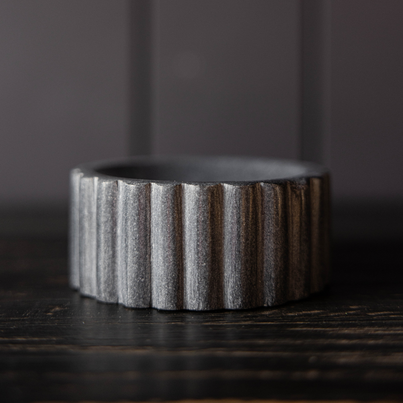 Textured ceramic dish brush holer on a dark surface with a dark background