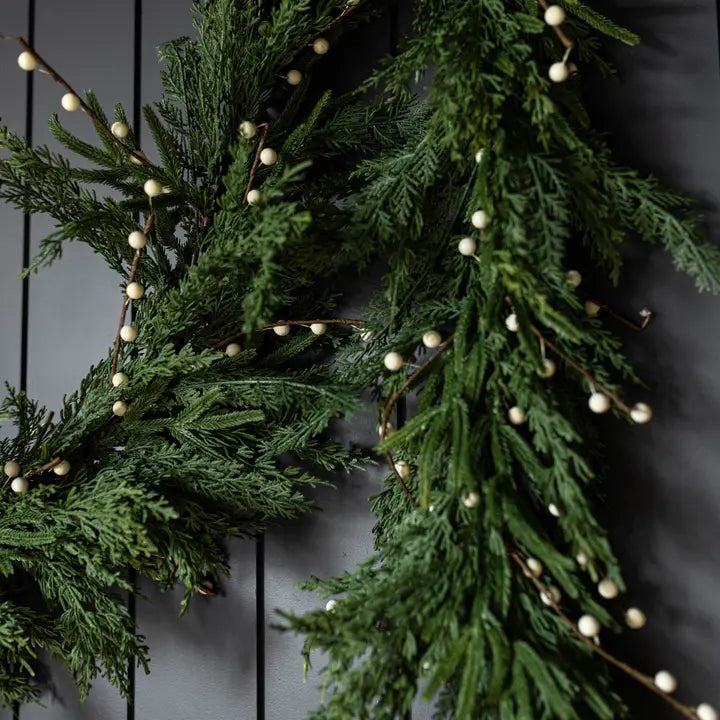Green garland with white berries on a dark background