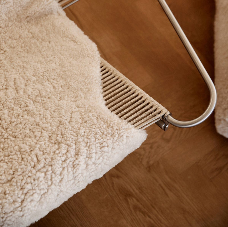 Beige textured rug on a wooden floor with a metal stand.