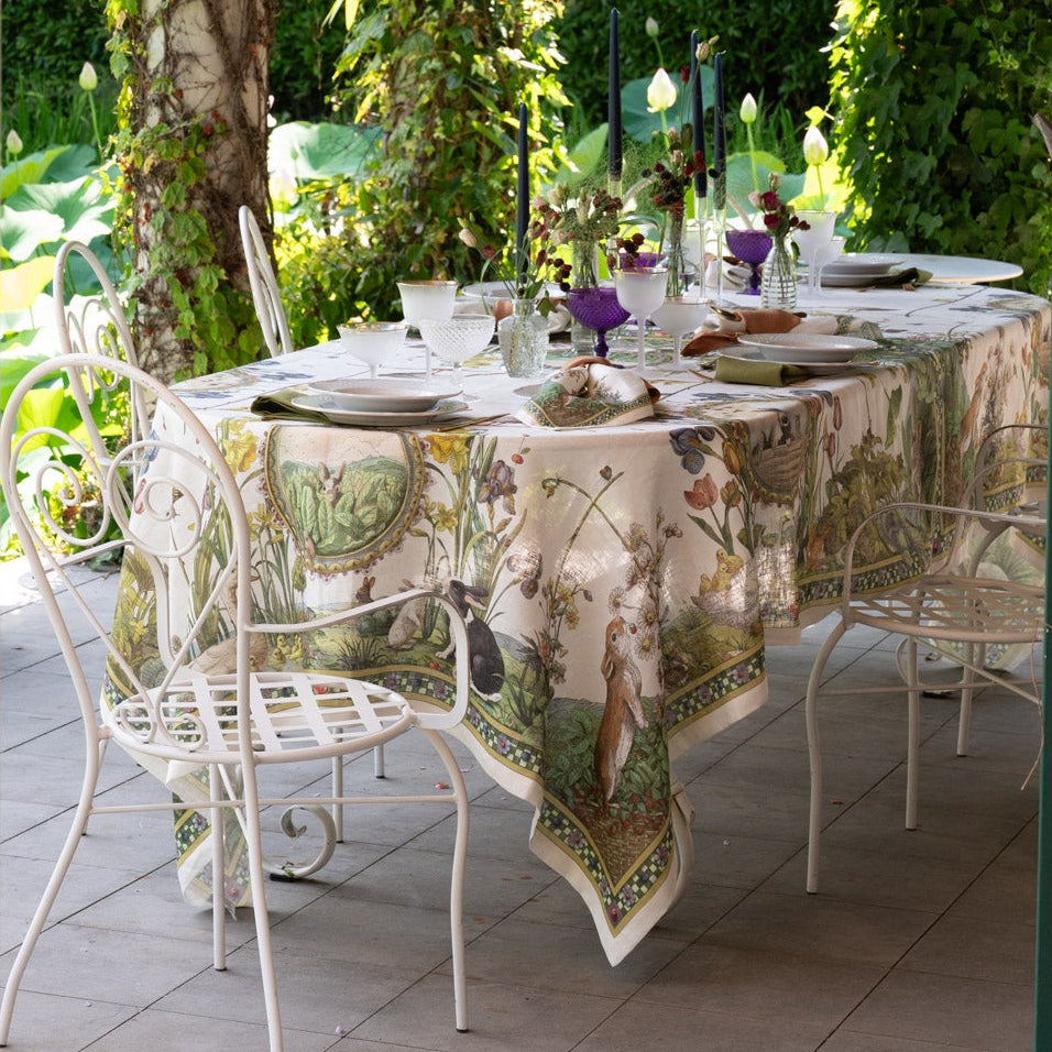Outdoor dining area with a table set for a meal, surrounded by greenery.